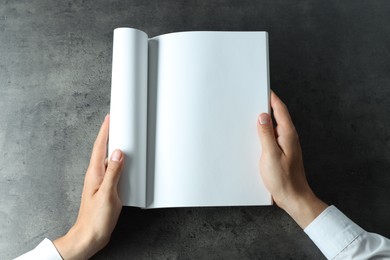 Photo of Man holding blank notebook at black textured table, top view. Mockup for design