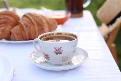 Stylish table setting with tea and croissants in spring garden