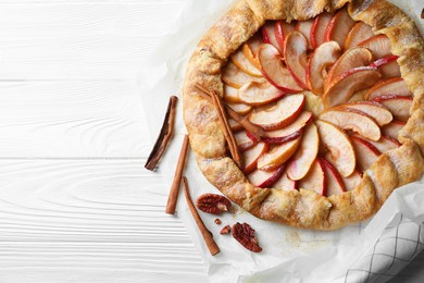 Delicious apple galette, cinnamon and pecans on white wooden table, flat lay. Space for text