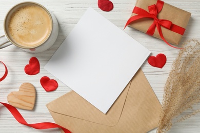 Flat lay composition with blank card on white wooden table, space for text. Valentine's Day celebration