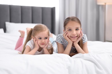Photo of Cute little sisters on bed at home