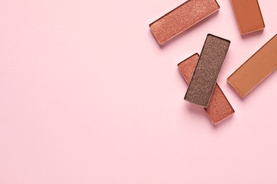 Different beautiful eye shadows on pink background, flat lay. Space for text