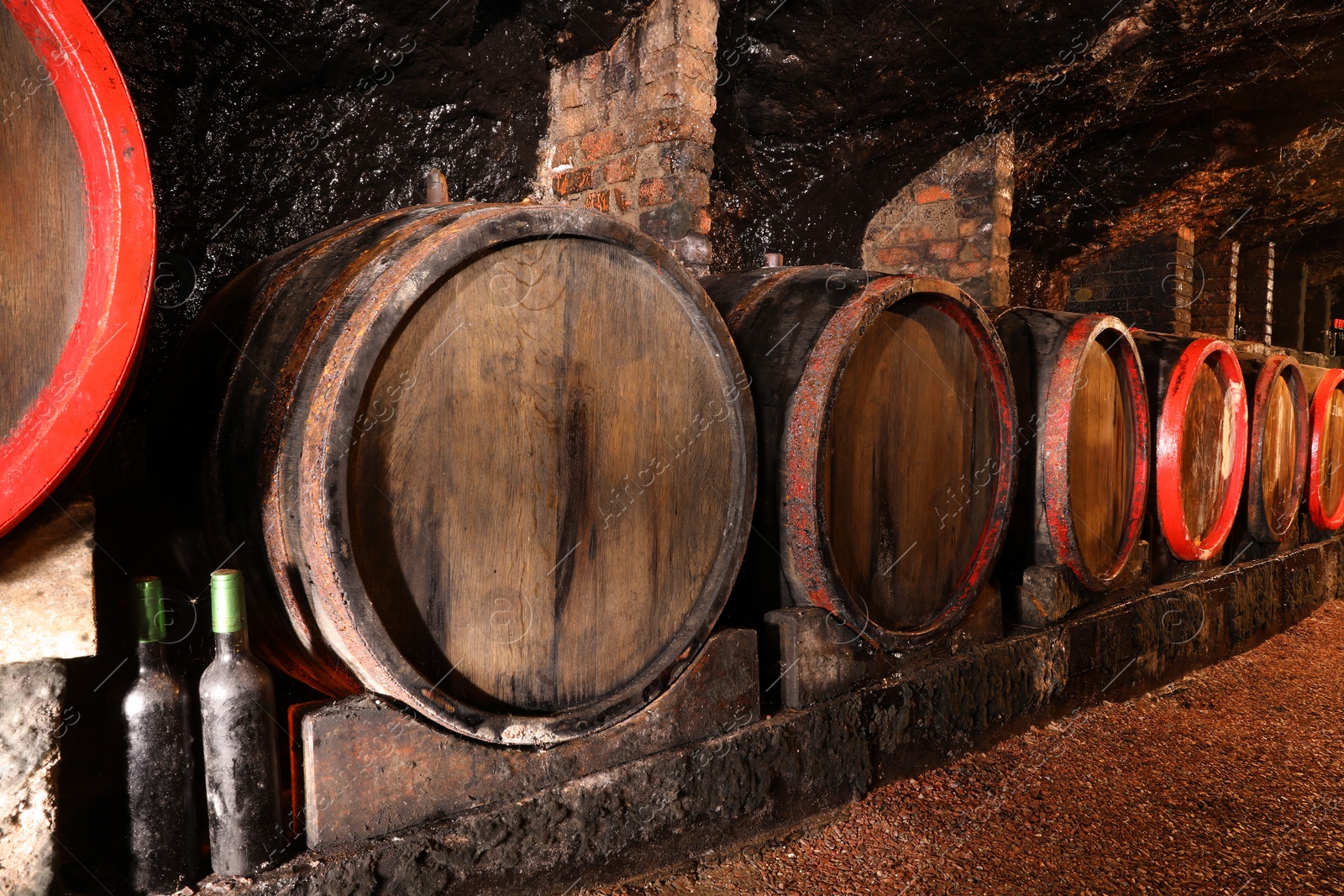 Photo of Many wooden barrels with alcohol drinks in cellar