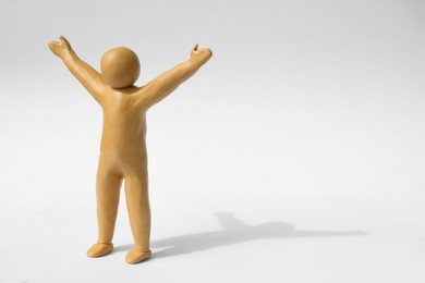 Photo of Human figure with arms wide open made of yellow plasticine on white background. Space for text