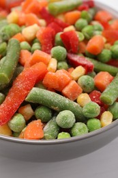 Photo of Mix of different frozen vegetables in bowl on white wooden table, closeup