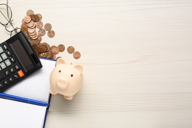 Calculator, piggy bank, notebook, pen and coins on white wooden table, flat lay. Space for text