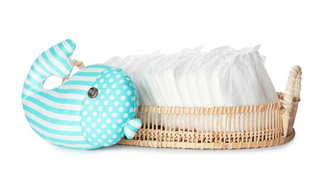 Photo of Wicker tray with disposable diapers and toy on white background