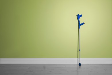 Photo of Elbow crutch near light green wall. Space for text