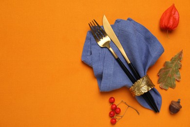 Photo of Flat lay composition with cutlery and napkin on orange tablecloth, space for text. Table setting