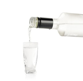 Photo of Pouring vodka from bottle in glass on white background