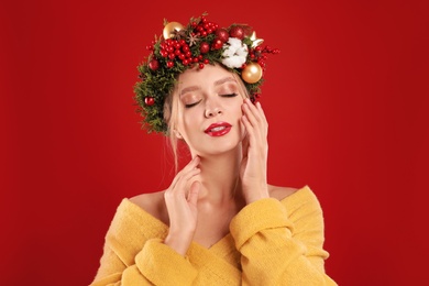 Photo of Beautiful young woman wearing Christmas wreath on red background