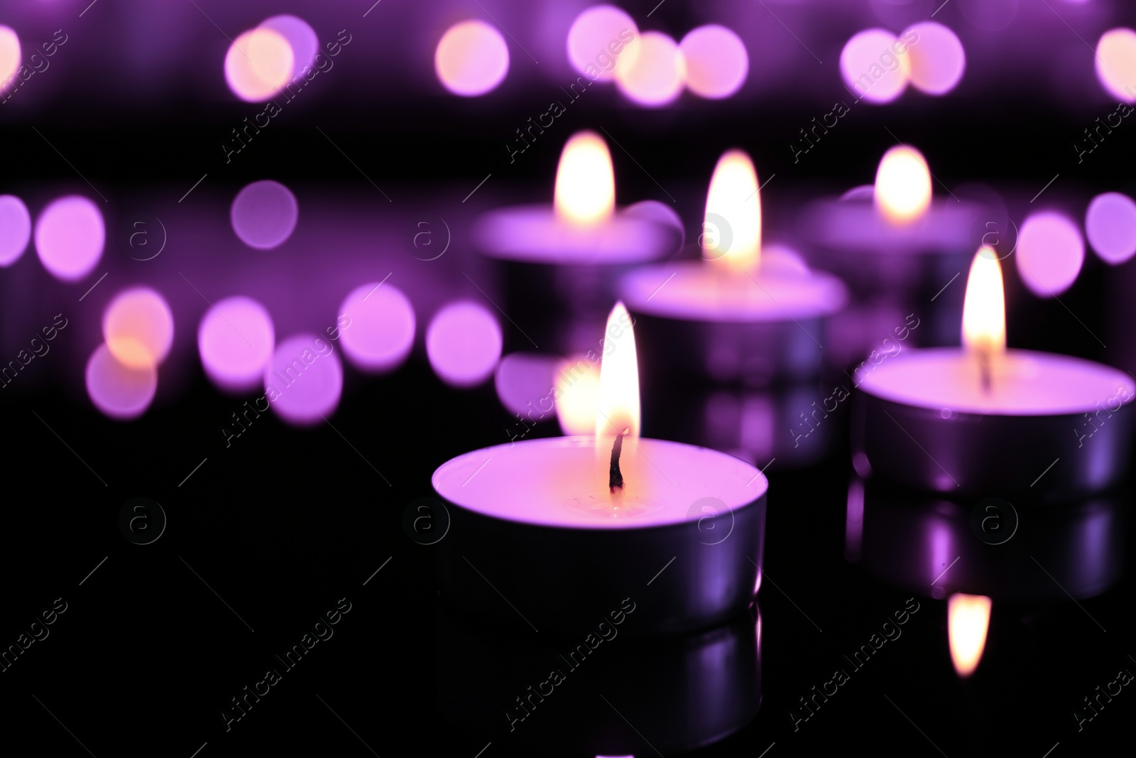 Image of Burning violet candle on black background, closeup. Funeral attributes