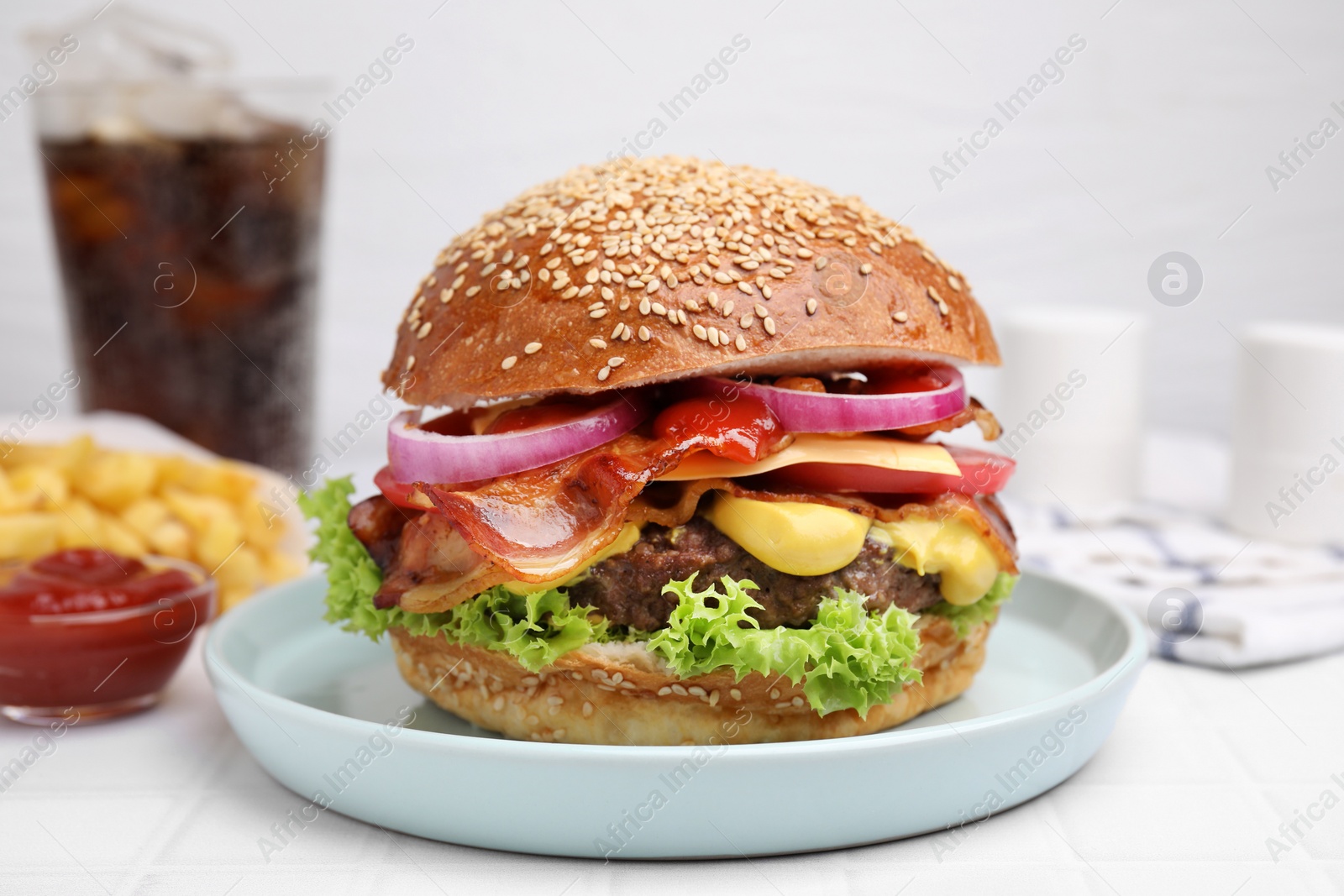 Photo of Delicious burger with bacon, patty and vegetables on white tiled table, closeup