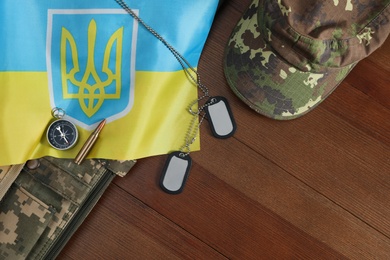 Photo of MYKOLAIV, UKRAINE - SEPTEMBER 26, 2020: Tactical gear and Ukrainian flag on table, flat lay. Space for text