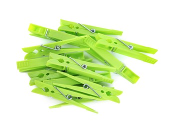 Bright green plastic clothespins on white background, top view