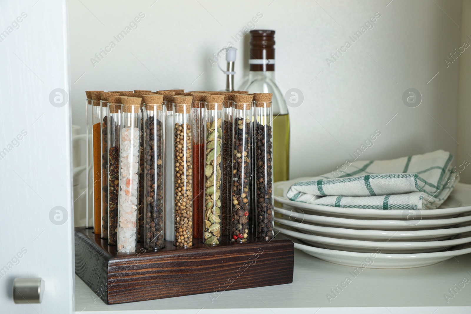 Photo of Glass tubes with different spices in kitchen cabinet