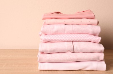 Photo of Stack of baby girl's clothes on wooden table