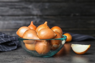 Bowl with fresh ripe onions on table