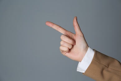 Photo of Businesswoman pointing at something on grey background, closeup. Finger gesture