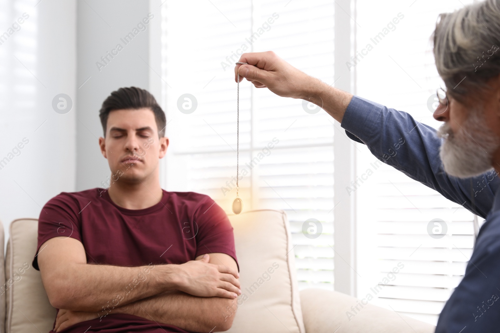 Photo of Psychotherapist using pendulum during hypnotherapy   session in office