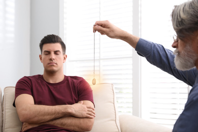 Psychotherapist using pendulum during hypnotherapy   session in office