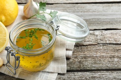 Photo of Jar with lemon sauce and ingredients on wooden table, space for text. Delicious salad dressing