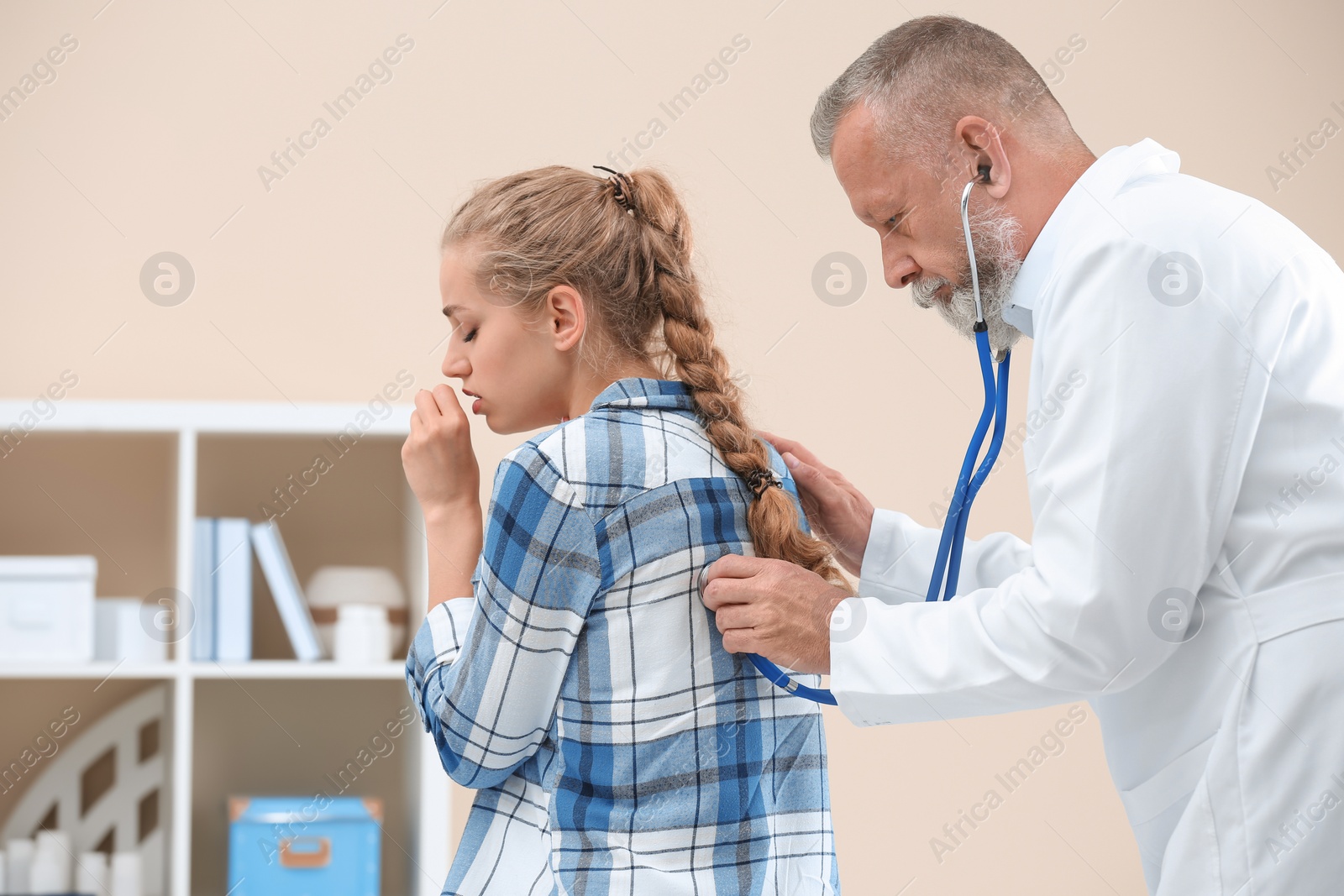 Photo of Doctor examining coughing young woman at clinic