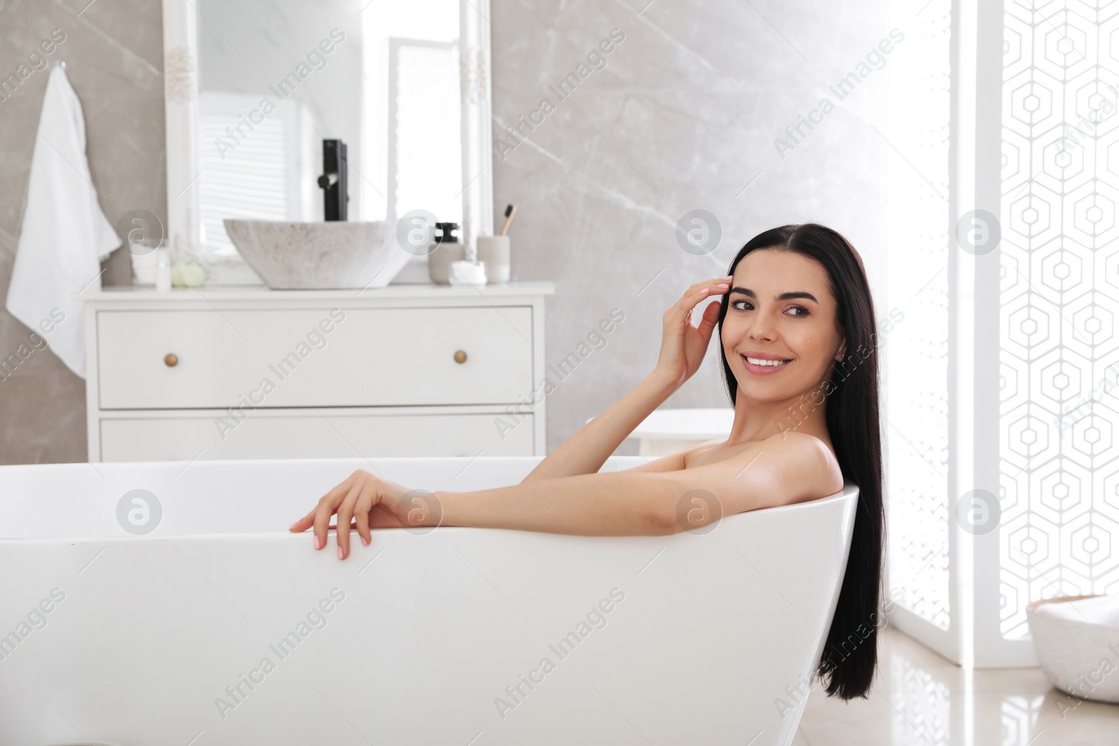 Photo of Beautiful young woman relaxing in bathtub at home