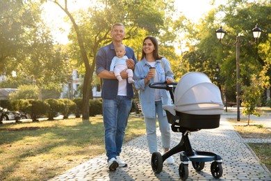 Photo of Happy parents walking with their baby in park on sunny day