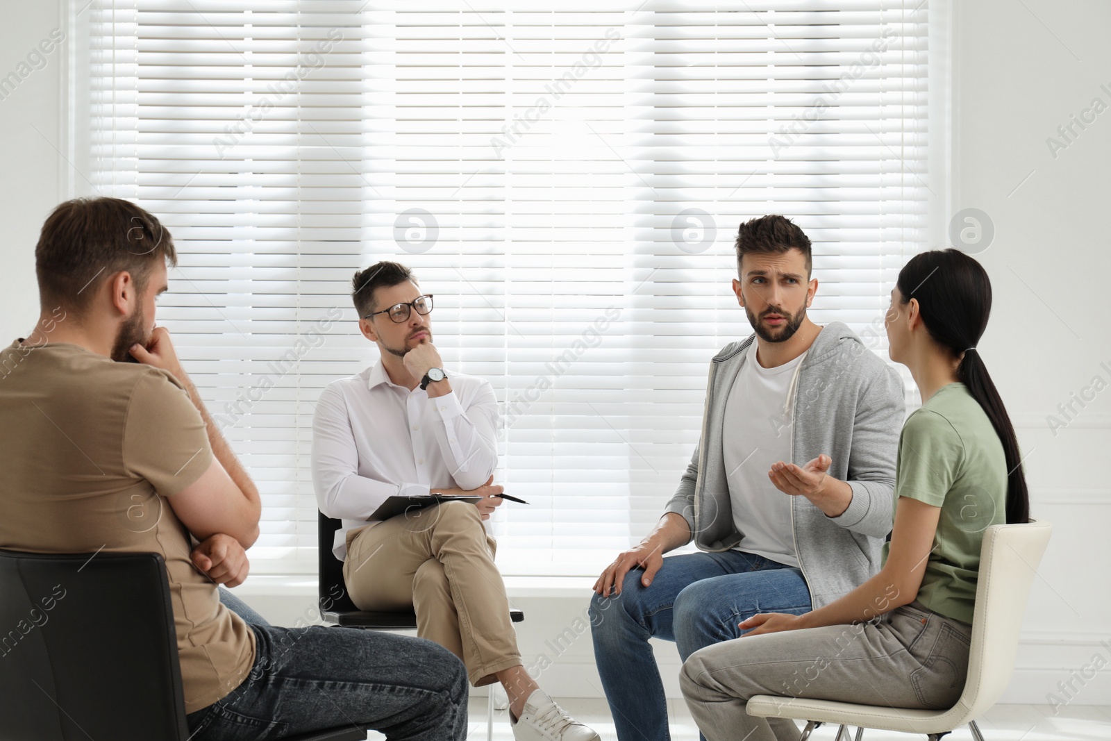 Photo of Psychotherapist working with group of drug addicted people at therapy session indoors