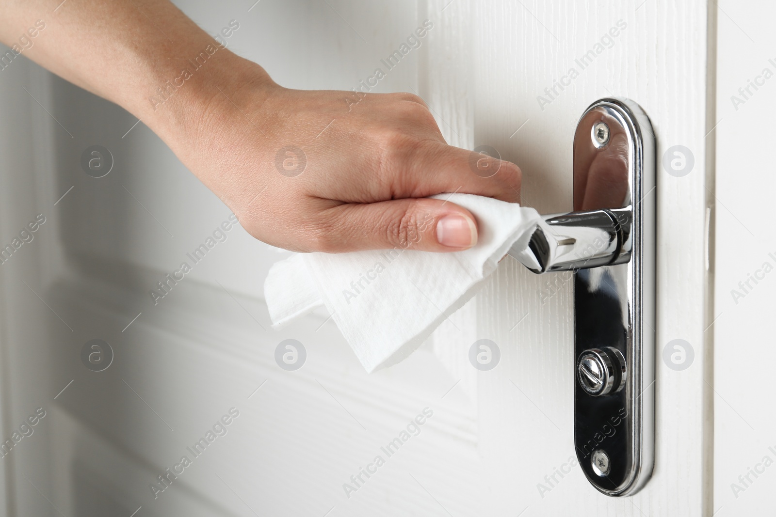 Photo of Woman using napkin to open door indoors, closeup