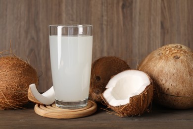 Photo of Glass of coconut water and nuts on wooden table