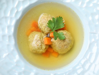 Photo of Tasty Jewish matzoh balls soup in dish, closeup