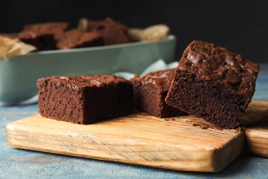 Photo of Wooden board with fresh brownies on table. Delicious chocolate pie