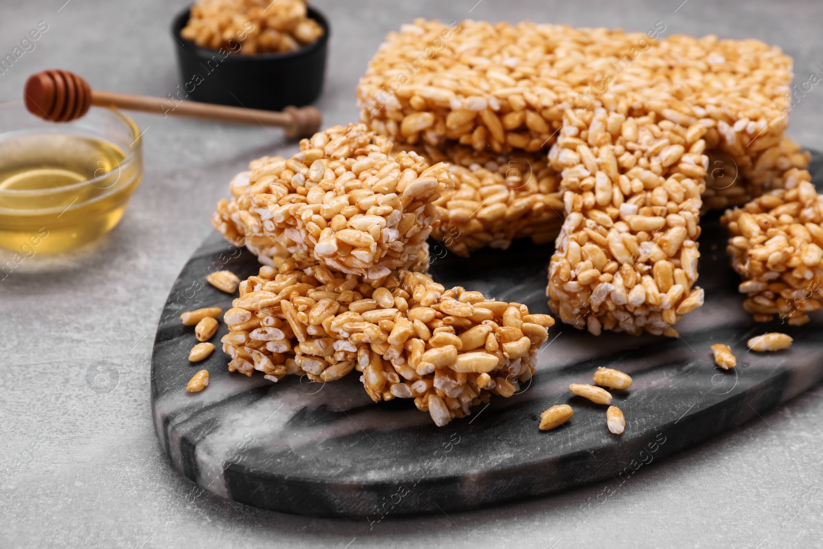 Photo of Board with puffed rice bars (kozinaki) on grey table, closeup