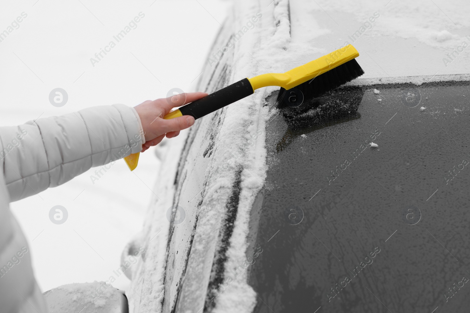 Photo of Man cleaning snow from car windshield outdoors, closeup