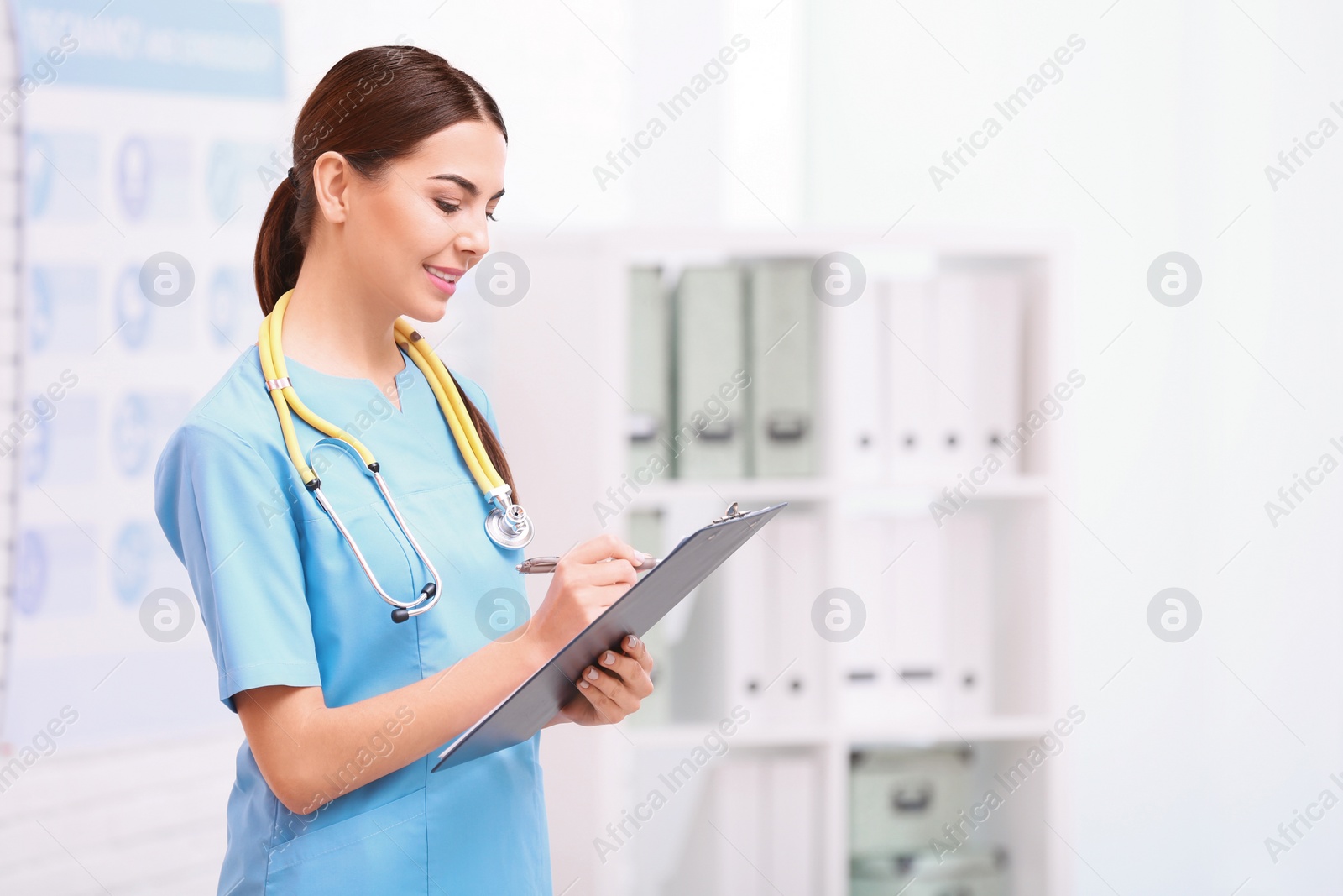 Photo of Portrait of medical assistant with stethoscope and clipboard in hospital. Space for text