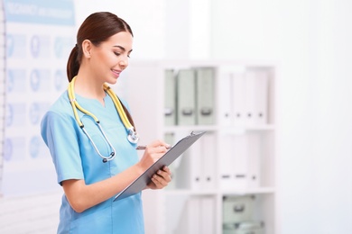 Portrait of medical assistant with stethoscope and clipboard in hospital. Space for text