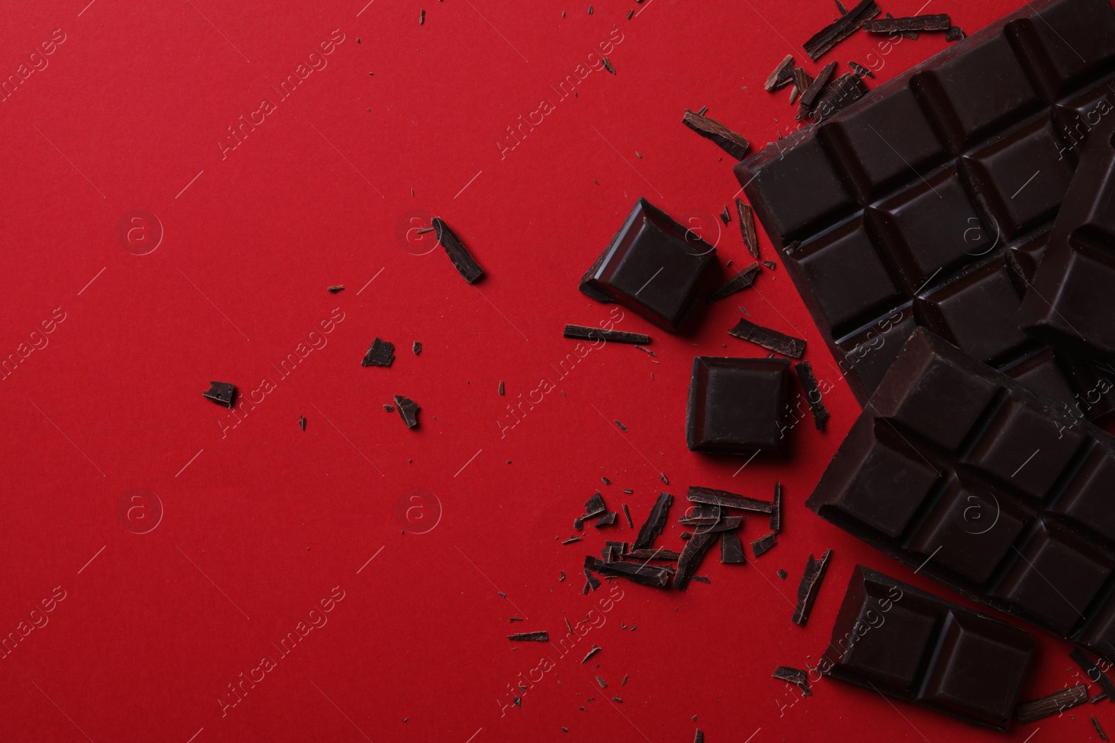 Photo of Tasty dark chocolate on red background, flat lay. Space for text