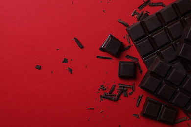 Tasty dark chocolate on red background, flat lay. Space for text