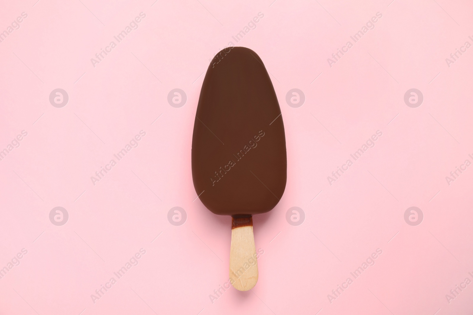 Photo of Ice cream glazed in chocolate on pink background, top view