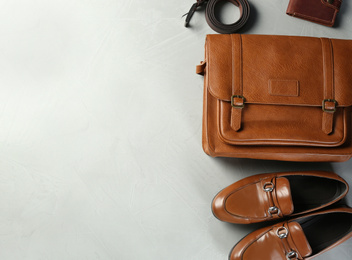 Photo of Flat lay composition with leather bag and shoes on light grey stone table. Space for text