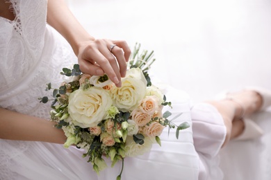 Young bride with beautiful wedding bouquet in room, above view