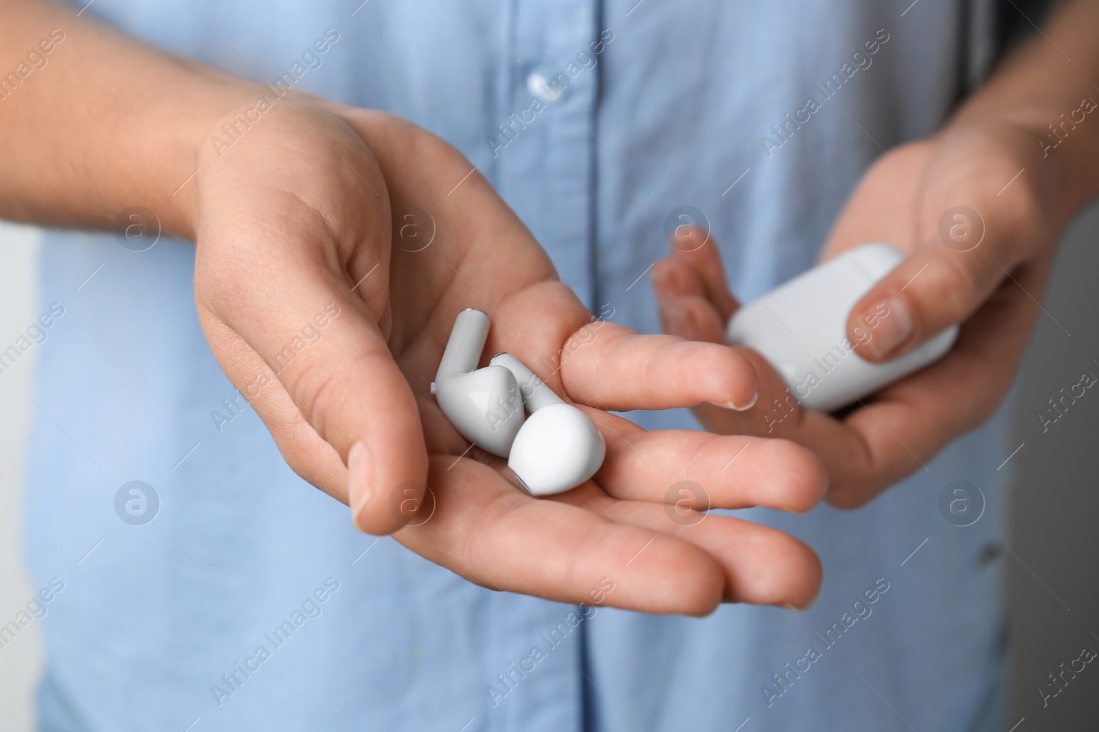 Photo of Woman holding wireless earphones and charging case, closeup