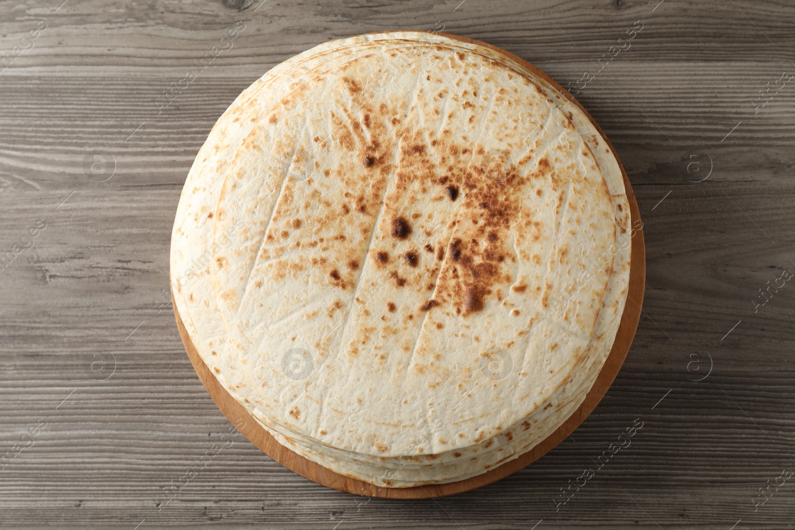 Photo of Many tasty homemade tortillas on wooden table, top view