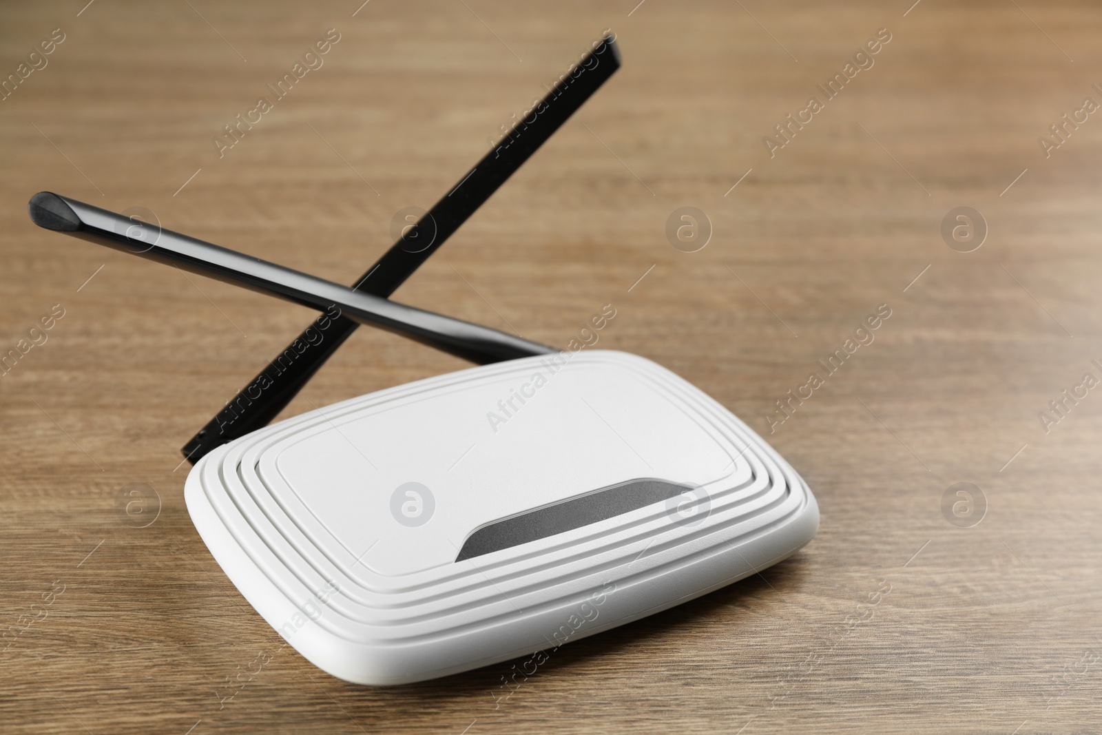 Photo of New modern Wi-Fi router on wooden background