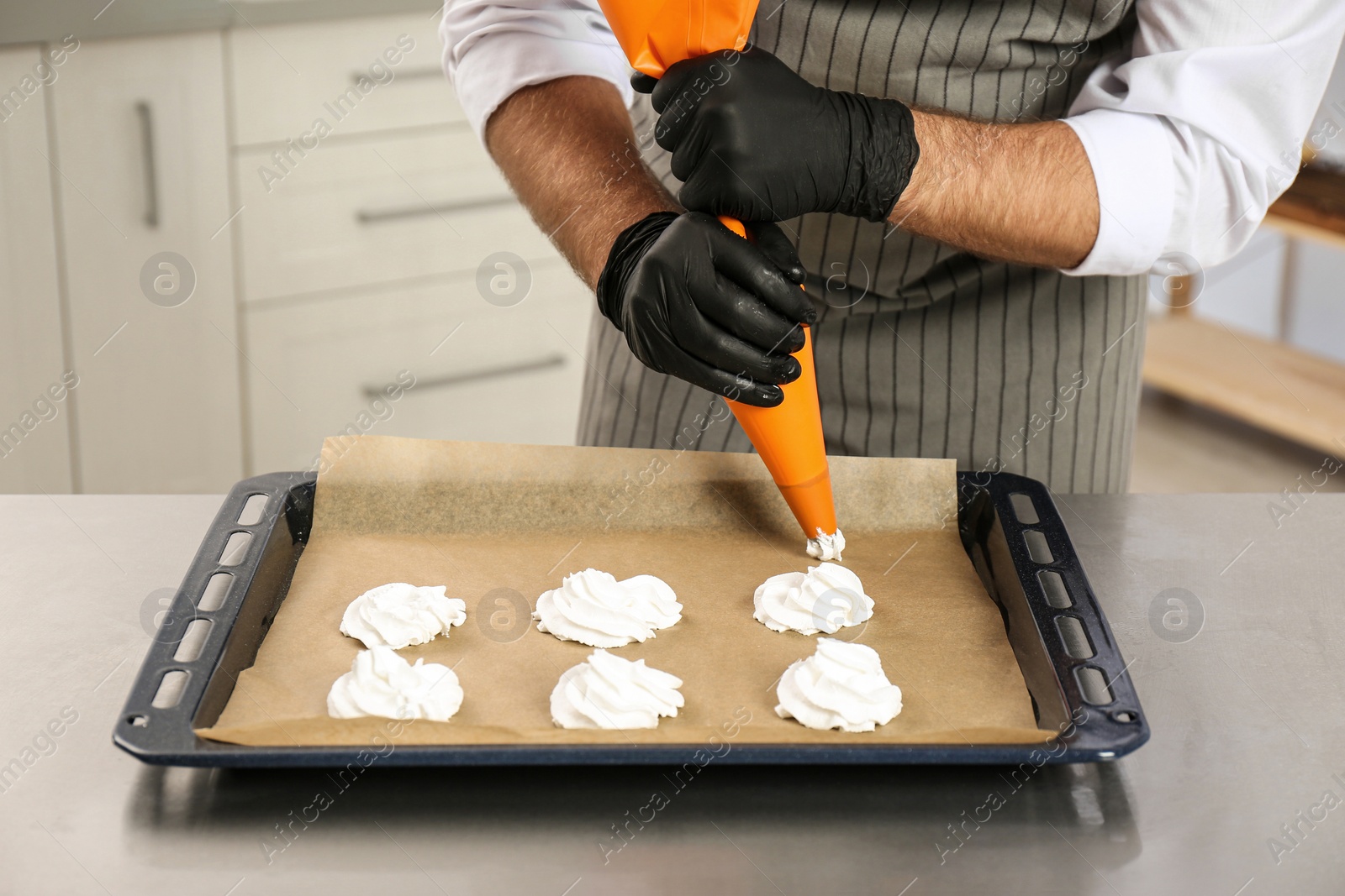 Photo of Pastry chef preparing meringues at table in kitchen, closeup