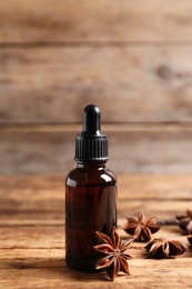 Photo of Bottle of essential oil and anise on wooden table