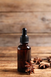 Bottle of essential oil and anise on wooden table