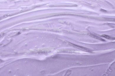 Clear cosmetic gel on violet background, above view